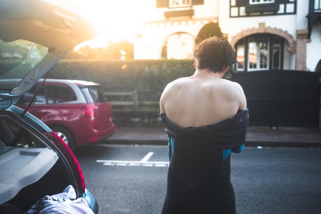 Young caucasian man taking off the neoprene after surfing on the beach.