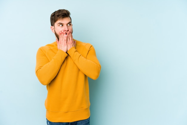 Young caucasian man thoughtful looking to a copy space covering mouth with hand.