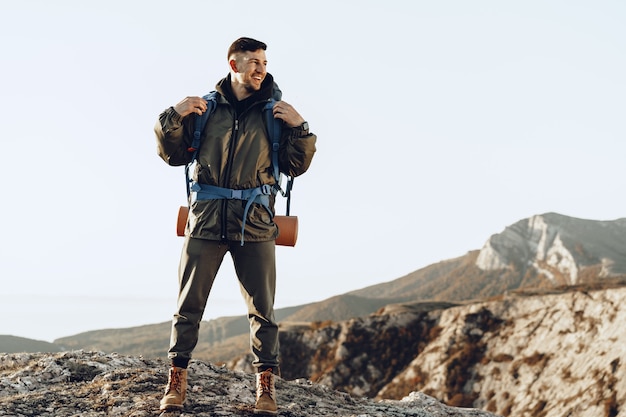 Young caucasian man traveler with big backpack hiking in the mountains