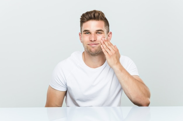 Young caucasian man using facial moisturizer