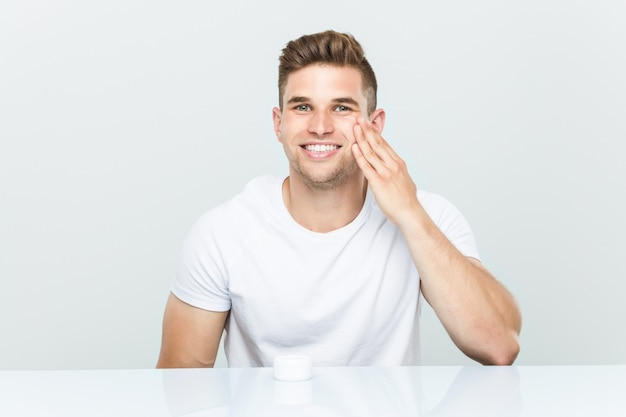 Young caucasian man using facial moisturizer