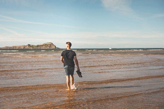 Young caucasian man walking at the beach