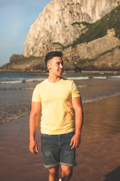 Young caucasian man walking at the beach