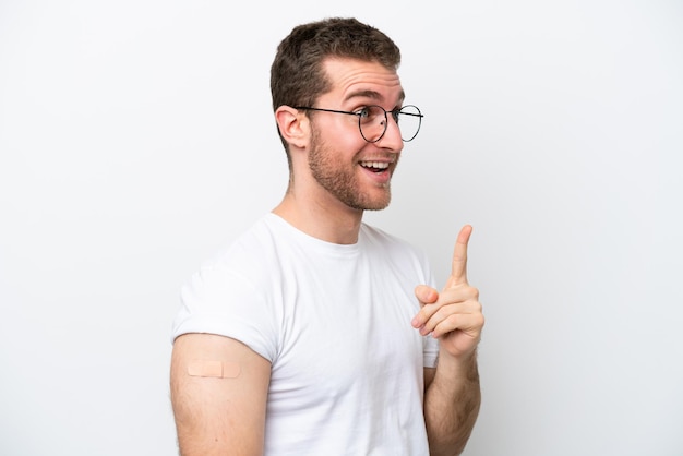 Young caucasian man wearing band aids isolated on white background intending to realizes the solution while lifting a finger up