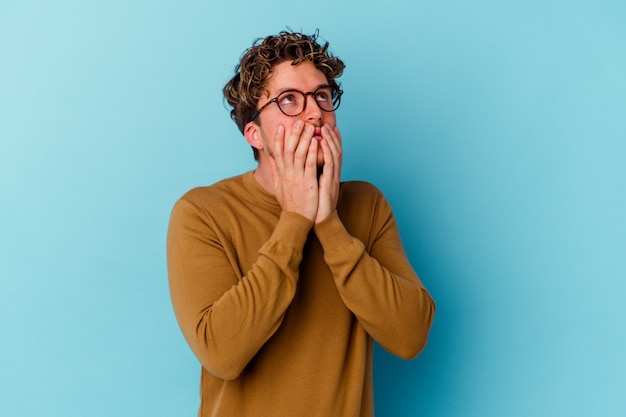 Young caucasian man wearing eyeglasses isolated on blue background whining and crying disconsolately.