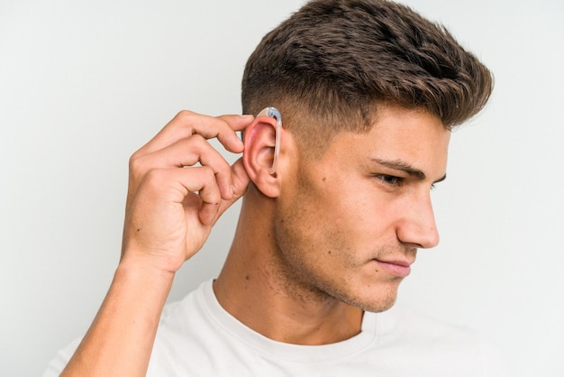 Young caucasian man wearing a hearing aid isolated on white background