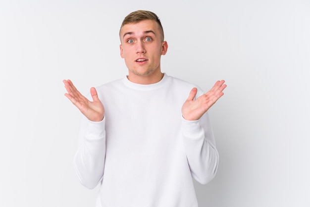 Young caucasian man on white wall surprised and shocked.