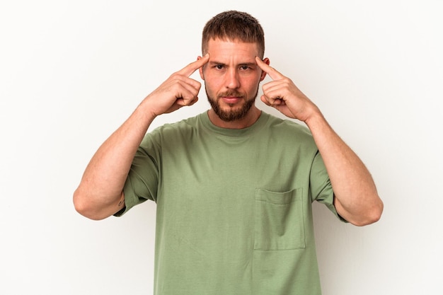 Young caucasian man with diastema isolated on white background focused on a task, keeping forefingers pointing head.