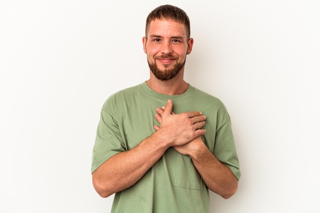 Young caucasian man with diastema isolated on white background has friendly expression, pressing palm to chest. Love concept.