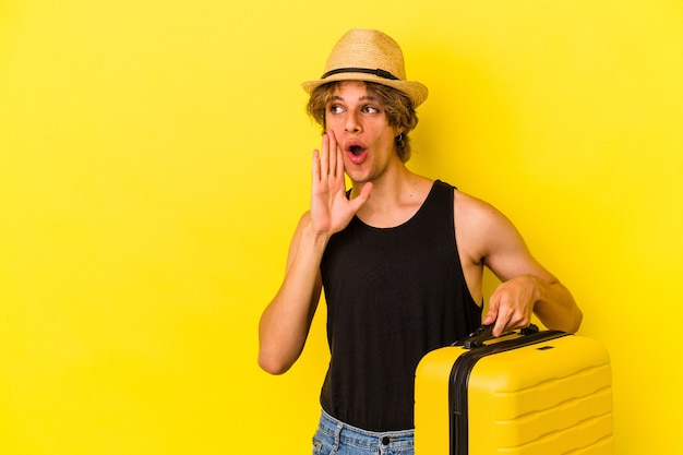 Young caucasian man with makeup going to travel isolated on yellow background  is saying a secret hot braking news and looking aside