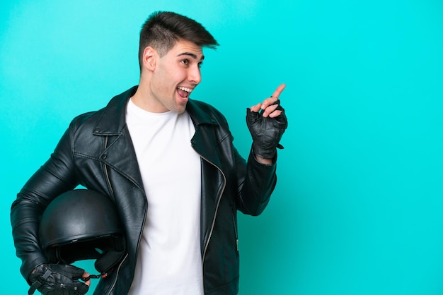 Young caucasian man with a motorcycle helmet isolated on blue background intending to realizes the solution while lifting a finger up