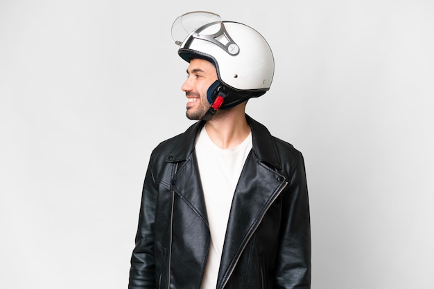 Young caucasian man with a motorcycle helmet over isolated white background looking side