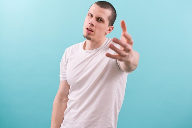 Young caucasian man with an open month stretching one hand at the camera Posing Model Clean Skin Grabbing Achieving Wide Single Stretching Trying Attractive Hipster Arm Cool