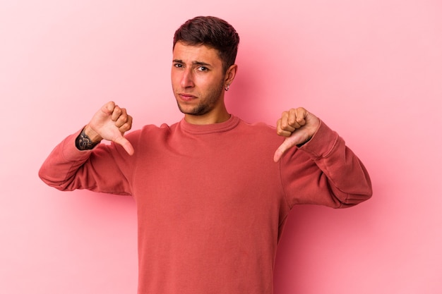 Photo young caucasian man with tattoos isolated on yellow background  showing thumb down, disappointment concept.