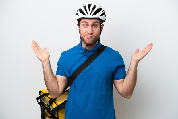 Young caucasian man with thermal backpack isolated on white background having doubts while raising hands