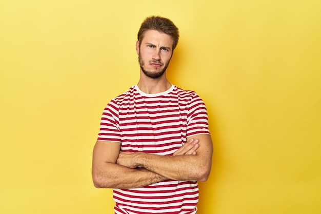 Photo young caucasian man on a yellow studio background unhappy looking in camera