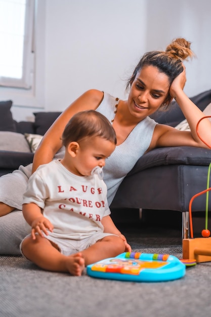 Young Caucasian mother with her son sitting on the floor next to the black sofa