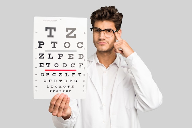 Young caucasian oculist man holding a optometry test isolated