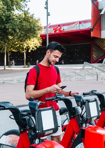 Young caucasian office worker renting a bicycle with his smart phone