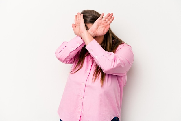 Young caucasian overweight woman isolated on white background keeping two arms crossed, denial concept.