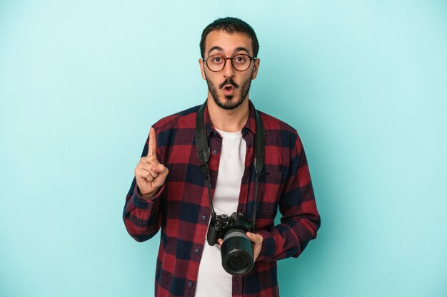 Photo young caucasian photographer man isolated on blue background having some great idea, concept of creativity.