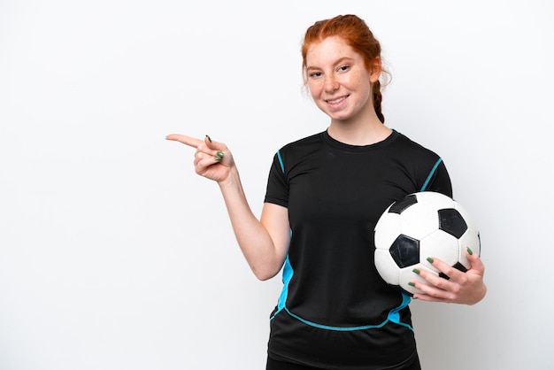 Young caucasian reddish football player woman isolated on white background pointing finger to the side