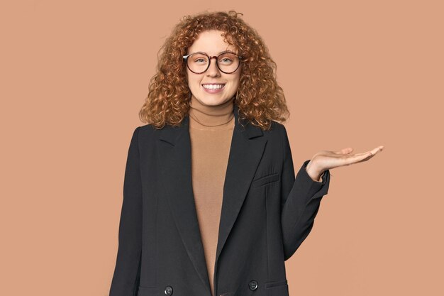 Young Caucasian redhead in business attire showing a copy space on a palm