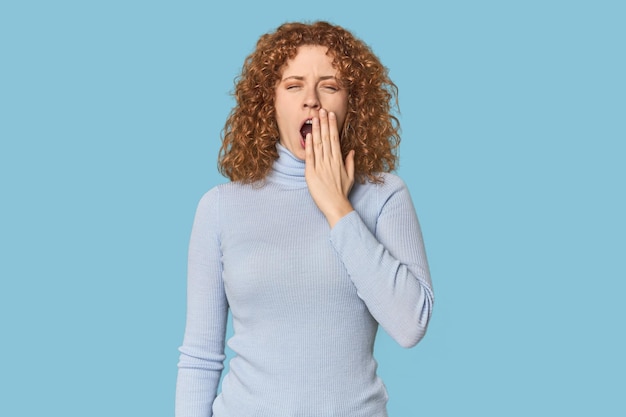 Photo young caucasian redhead woman yawning showing a tired gesture covering mouth with hand