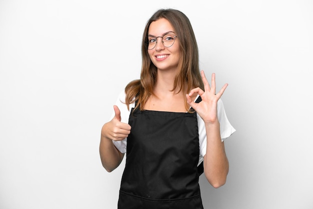 Young caucasian restaurant waiter woman isolated on white background showing ok sign and thumb up gesture