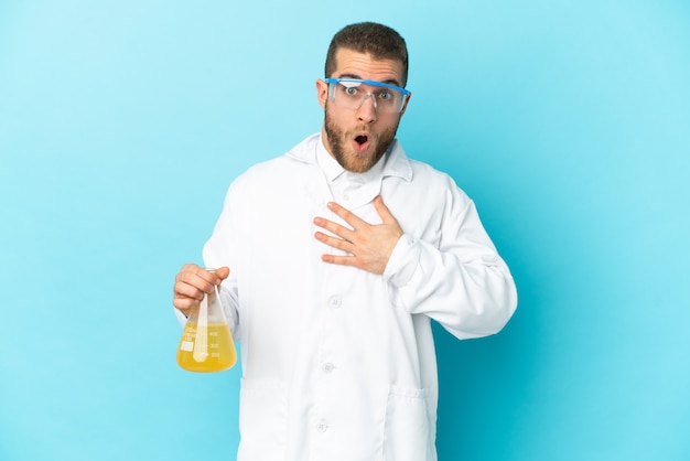 Young caucasian scientific man isolated on blue surprised and shocked while looking right