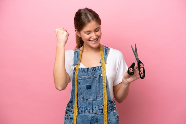 Young caucasian seamstress woman isolated on pink background celebrating a victory