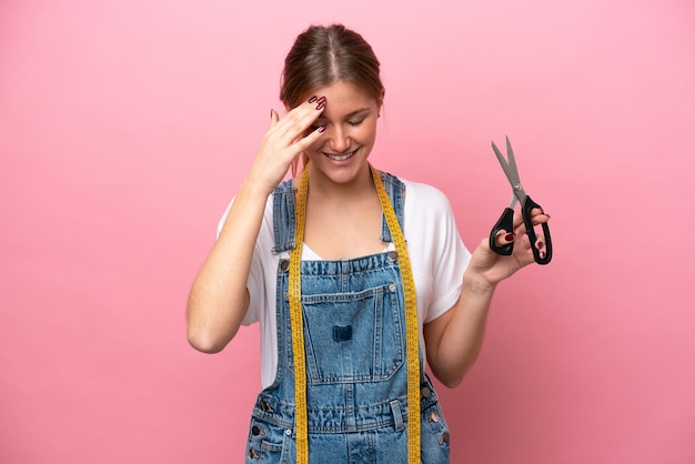 Young caucasian seamstress woman isolated on pink background laughing