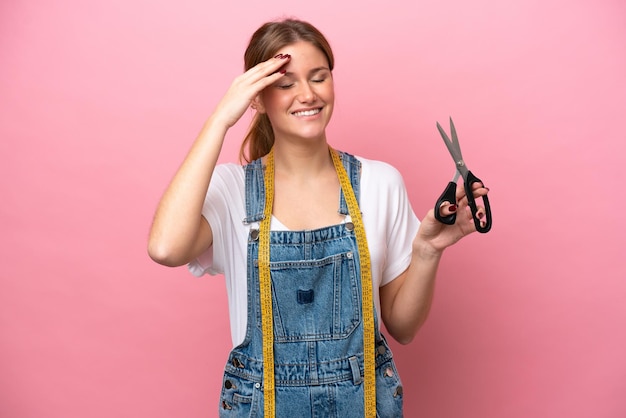 Young caucasian seamstress woman isolated on pink background smiling a lot