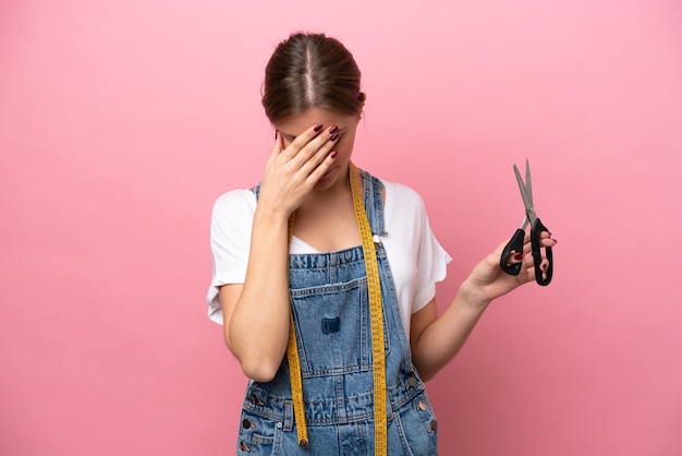 Young caucasian seamstress woman isolated on pink background with tired and sick expression