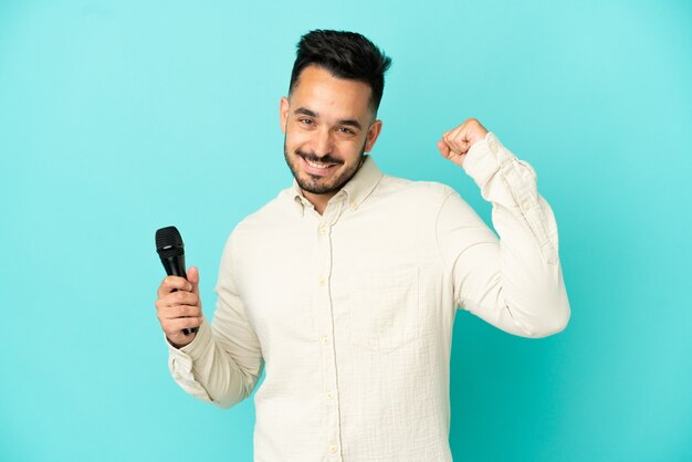 Young caucasian singer man isolated on blue background celebrating a victory