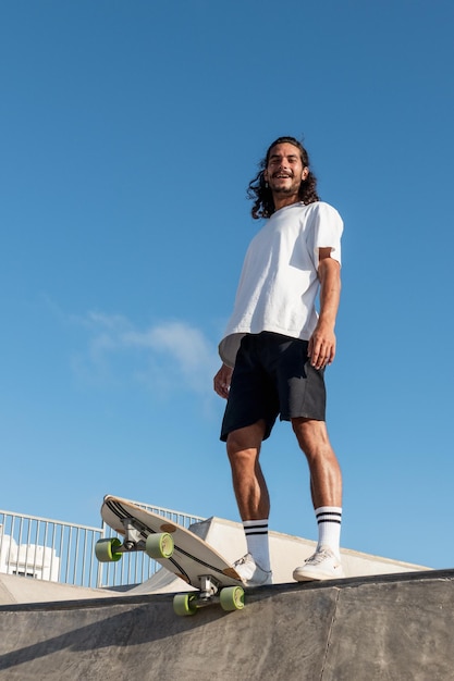 Young caucasian skater laughing at the skate park He is wearing summer clothes