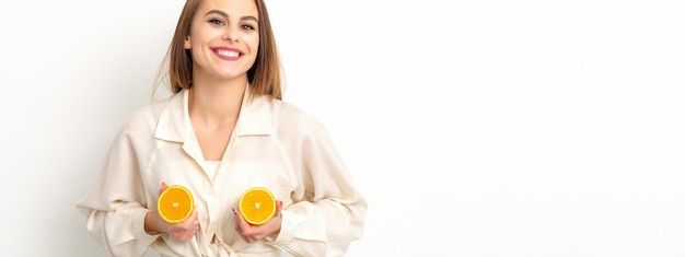 Young Caucasian smiling woman holding slices orange over isolated white background breast health concept