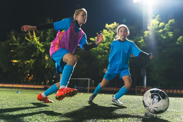 Photo young caucasian soccer player girls in action soccer practice at night