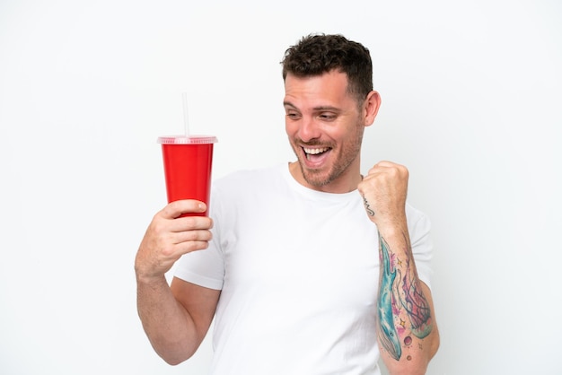 Young caucasian soda holding soda isolated on white background celebrating a victory