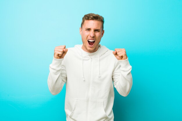 Young caucasian sport man cheering carefree and excited. Victory concept.