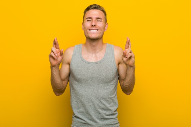 Young caucasian sport man crossing fingers for having luck