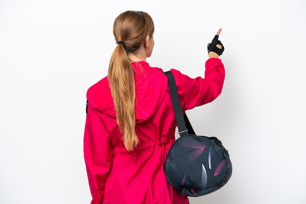 Young caucasian sport woman isolated on white background pointing back with the index finger