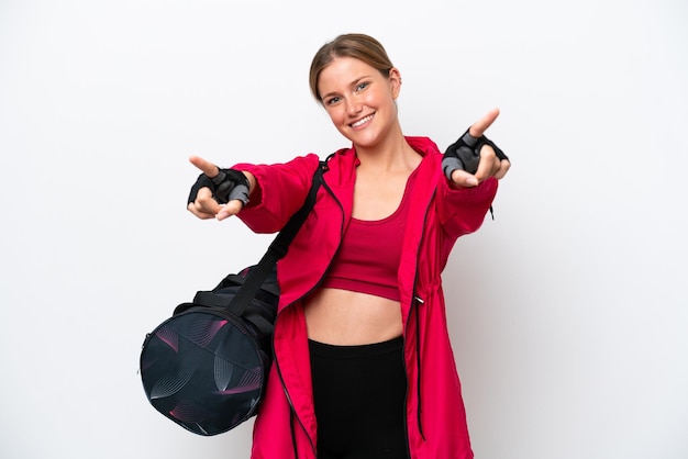 Young caucasian sport woman isolated on white background points finger at you while smiling