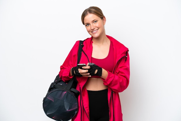 Young caucasian sport woman isolated on white background sending a message with the mobile