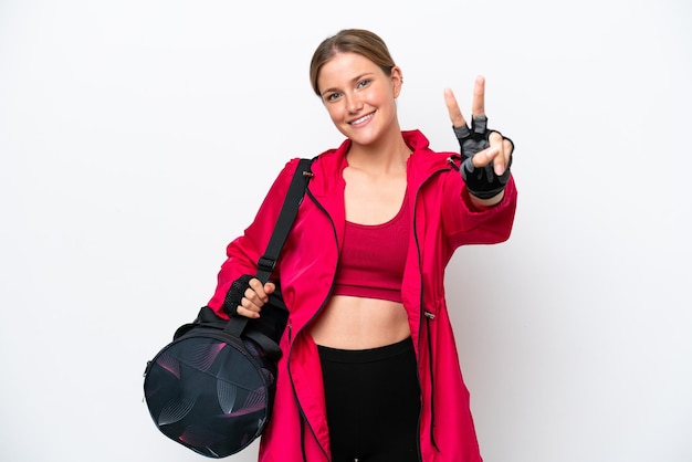 Young caucasian sport woman isolated on white background smiling and showing victory sign