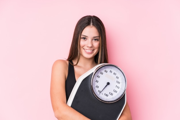 Young caucasian sporty woman holding a scale