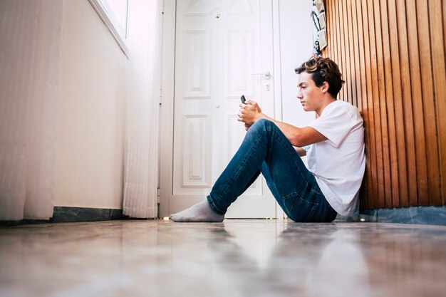 Young caucasian teenager using the smartphone on floor