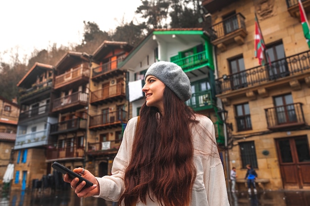 Young caucasian tourist woman using the smartphone in an old town.