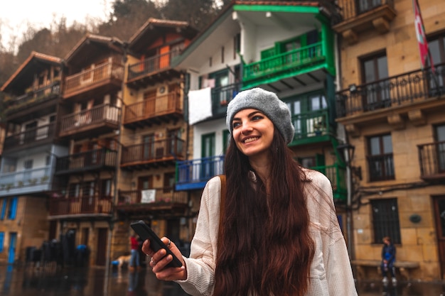 Young caucasian tourist woman using the smartphone in an old town.