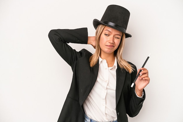 Young caucasian wizard woman holding wand isolated on white background touching back of head, thinking and making a choice.